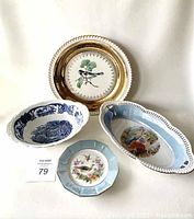 Four vintage decorative dishes displayed upright and flat, showing detailed designs and rims