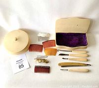 Full view of grooming set including dish with lid, combs, grooming tools, hairpins, and decorative hair comb and clip.