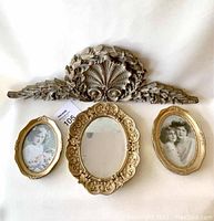 Full view of three gold picture frames and carved wall ornament arranged for display