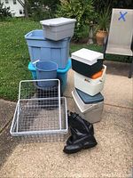 Multiple stacked plastic storage bins, small coolers, metal shelf racks, blue bucket, and black Rainfair boots size 10.