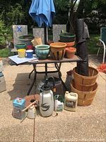 Full lot with assorted ceramic and plastic planters, Round Up sprayer, herbicides and cleaning supplies displayed on patio