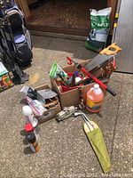 Overview of all items including bottles, boxes, car jack, and tools spread on ground