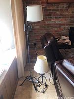 Full view of both lamps showing floor lamp standing next to a chair and table lamp on floor in front