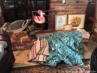 View of stitched art pieces, wooden goose, owl statuette, quilts and wall shelf arranged near brick wall