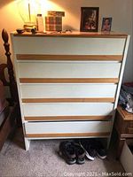 Front view of Henry Link chest of drawers showing five drawers with wood trim, cream colored body, with some wear visible at the base and top.