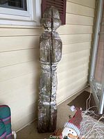 Full view of tall wooden pillar with weathered surface, showing wear and peeling.