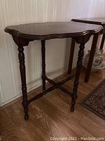 Full view of the spindle leg accent table with carved apron and irregular shaped top showing overall wear and finish condition.