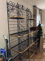 Full view of wrought iron bakers rack with brass trim and 4 shelves