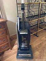 Full front view of Hoover Power Max vacuum cleaner showing overall design and extra vacuum bags attached to hose.