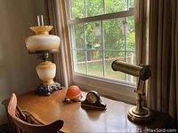 Desk lamp, turtle lamp, and mantel clock on desk by window