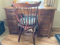 Desk and chair set viewed from the back showing the chair and drawer fronts of the desk