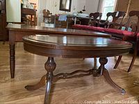 Side view of the oval coffee table showing the table top and legs in a room with other furniture.