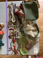 Flat lay photo of necklaces, pins, watches, bracelets, and handbags on a table.