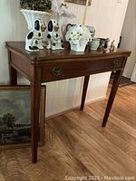 Walnut accent table with brass drawer pulls and tapered legs, showing right side and front