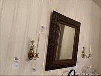 Wide shot showing entire mirror and both wall sconces mounted on wall.