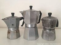 Three stove top espresso coffee makers, large middle is Zanzibar, two smaller ones Bialetti, showing overall condition and size difference