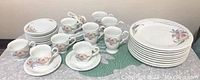 Full set with stacked dinner plates, cups, mugs, saucers all displayed on table.