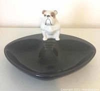 Front view of black ceramic ashtray with bulldog figurine on edge