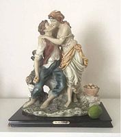 Full view of the vintage ceramic sculpture showing the kissing couple on a naturalistic base with basket and log, viewed front.