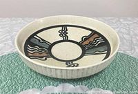 Front angled view of round pottery bowl showing exterior texture and interior painting