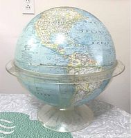 Full view of vintage National Geographic globe displaying North and South America, sitting in clear acrylic stand on a surface.