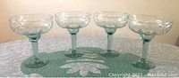 Four crystal margarita glasses arranged on a table, showing their shape and design