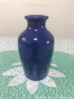 Front view of royal blue pottery bud vase on green mat