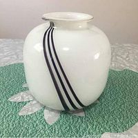 Round white glass vase with black stripes and gold rim, front angle.