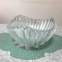 Side-angle view showing ribbed vertical cut crystal design and scalloped edge with small feet below bowl.