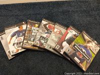 Front view of 7 PlayStation 2 game cases stacked in a slight arc showing cover art and titles.