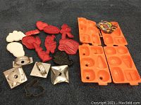 Full view of all cookie cutters and molds, showing metal cutters, plastic cutters in various Halloween and Valentine shapes, and two orange plastic molds.