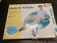 Box displaying man sitting on inflated blue Astro Chair.