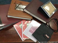 Top view of seven photo albums with several red and white protective covers and a black passport pouch with Black's logo.