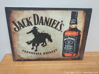 Front view of the Jack Daniel's Tennessee Whiskey canvas print on a wooden floor, showing the full design with a whiskey bottle and cowboy silhouette.
