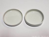 Top view of two small white ceramic Rosenthal dishes, showing interior surfaces, one smooth sided and one ridged.