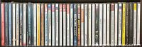 A horizontal row of 27 CD jewel cases showing spines with artist and album names from various music genres