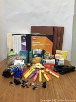 Various office supplies arranged on a table including pens, markers, folders, staplers, paper clips, elastics and sticky notes.