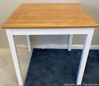 Front view of small square dining table with light wood top and white legs, showing overall condition.
