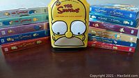 Photo showing The Simpsons DVD boxed sets for seasons 1 through 12 arranged in two groups with the special metal tin for season 6 in the middle.