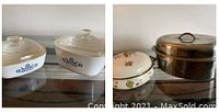 Two Corningware blue cornflower casserole dishes with glass lids, heavy serving dish and stainless steel roasting pan shown