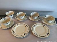 Overall view of six small plates, five teacups, and four saucers arranged on a table showing the pattern and condition.