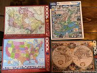 Four 1000-piece puzzle boxes arranged on a wooden floor showing the front cover images and box titles.