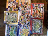 Overhead photo showing all 8 White Mountain puzzle boxes arranged on a wooden floor, showcasing variety of US themed puzzles.