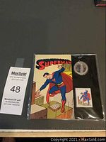Full set in sealed plastic packaging showing Superman artwork, lenticular coin, and stamp.