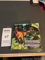 Front view of the sealed colorful folder for Discover Canada's Dinosaurs 2019 coin set with dinosaur artwork and three visible 25 cent coins.
