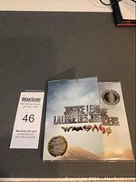 Original sealed folder showing Justice League logo and coin window with lenticular coin inside.