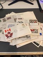 Pile of Canadian First Day Covers and postal items arranged on a flat surface showing variety of envelopes with stamps and postmarks.