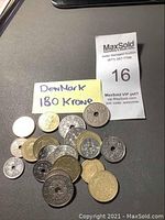 Top view of seventeen old Danish coins laid on a dark surface. Includes a handwritten note stating 'Denmark 180 Krone' and auction lot tag number 16.