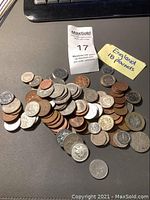 Photo showing a pile of various British coins of different sizes and colors on a surface, including copper pennies and bi-metallic pounds.