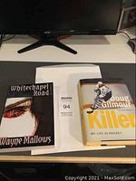 Two autograph books placed flat on a desk beneath a monitor: "Whitechapel Road" and "Killer: My Life in Hockey"